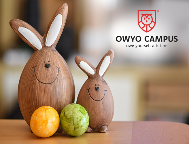 Zwei Holzkunstwerke die jeweils einen Osterhasen darstellen, davor zwei Eier und im Hindergrund das OWYO CAMPUS Logo